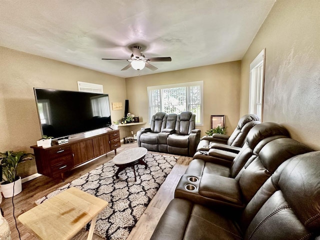 living room with baseboards, wood finished floors, a ceiling fan, and a textured wall