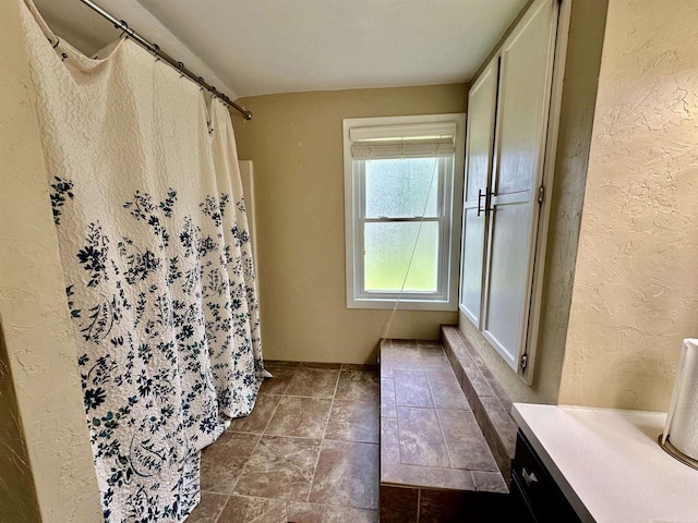 full bathroom featuring a shower with shower curtain and a textured wall