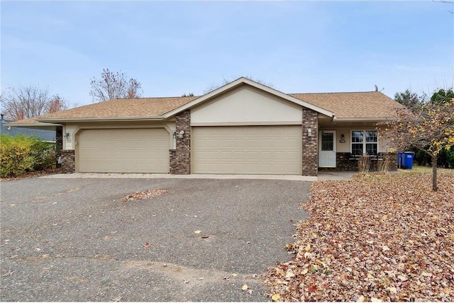 ranch-style house featuring aphalt driveway, an attached garage, brick siding, and a shingled roof