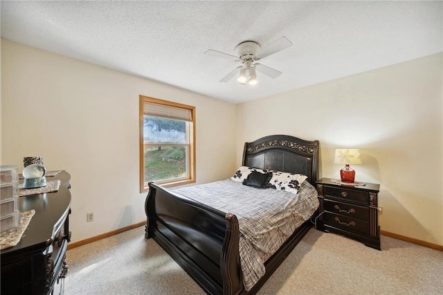 bedroom featuring baseboards, light colored carpet, a ceiling fan, and a textured ceiling