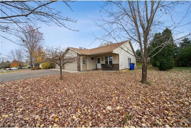 view of front facade featuring aphalt driveway, covered porch, and a garage