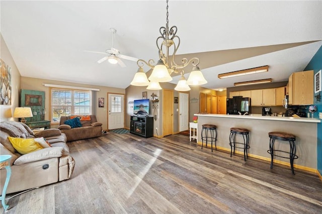 living area featuring baseboards, lofted ceiling, wood finished floors, and a ceiling fan