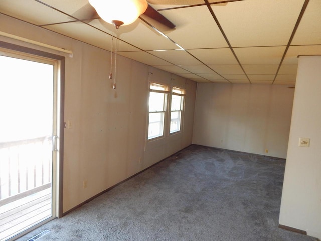 carpeted empty room featuring a paneled ceiling, visible vents, and baseboards