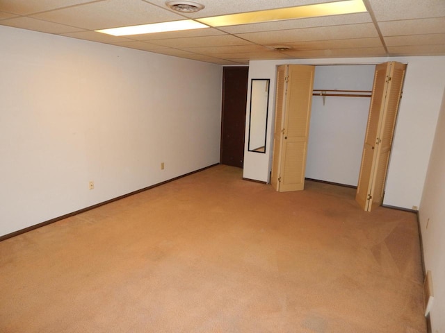 unfurnished bedroom featuring a drop ceiling, light colored carpet, and baseboards