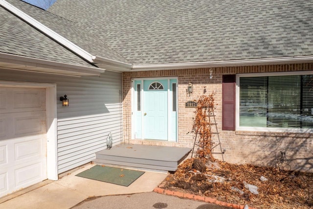 property entrance with brick siding, an attached garage, and roof with shingles