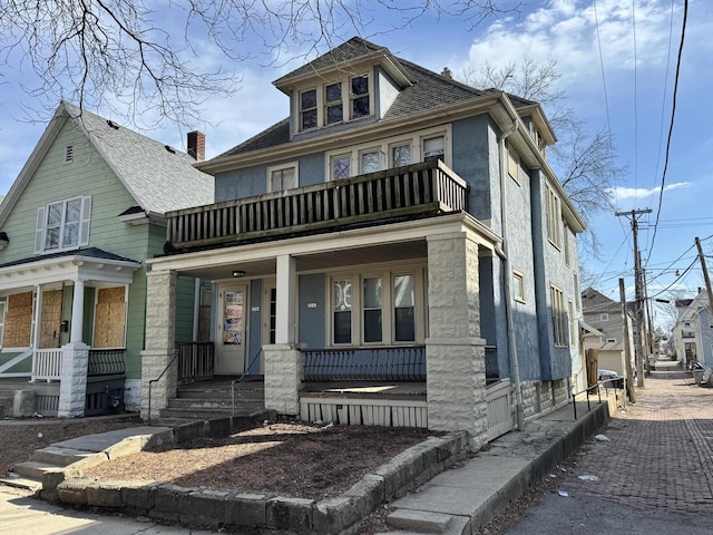 american foursquare style home with roof with shingles, covered porch, and a balcony