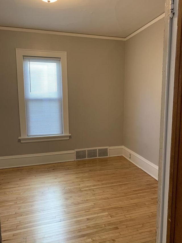 spare room with visible vents, baseboards, ornamental molding, and light wood finished floors