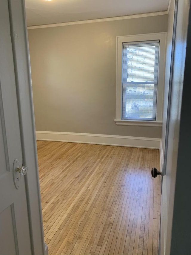 empty room featuring hardwood / wood-style flooring, baseboards, and ornamental molding