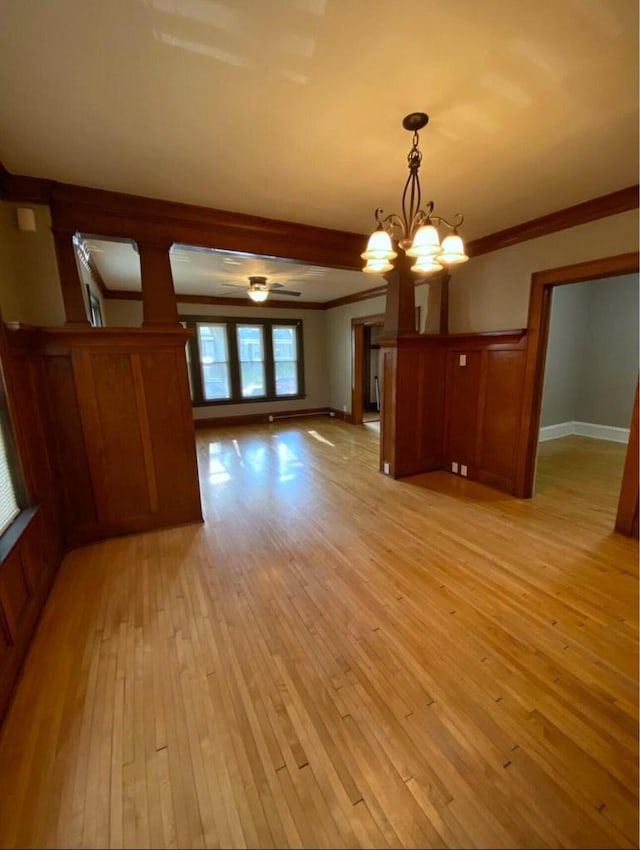 unfurnished living room with a notable chandelier, light wood-style floors, and crown molding