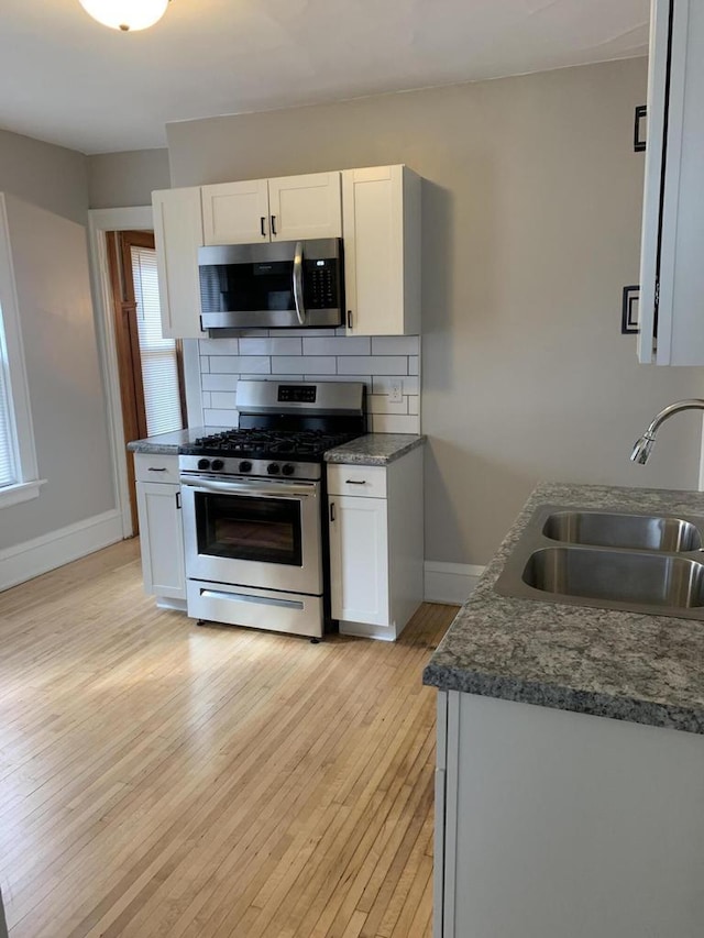 kitchen featuring a sink, white cabinets, tasteful backsplash, and stainless steel appliances