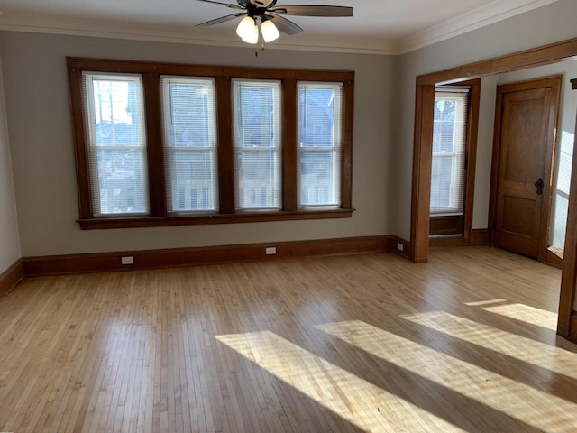 spare room featuring crown molding, light wood-style flooring, a ceiling fan, and baseboards