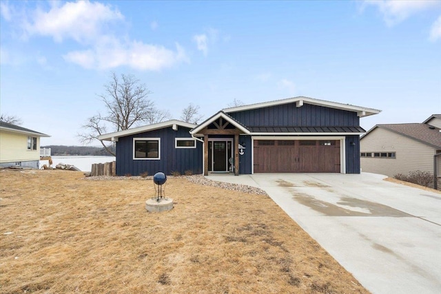 view of front of house featuring board and batten siding, concrete driveway, metal roof, a garage, and a standing seam roof