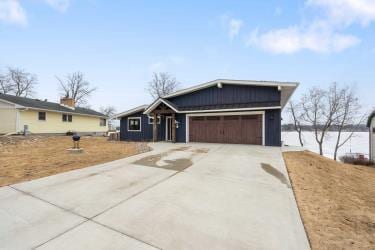 view of front of property with a garage, a water view, and driveway