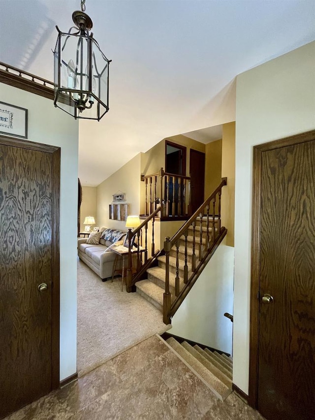 stairs featuring baseboards, an inviting chandelier, and carpet flooring