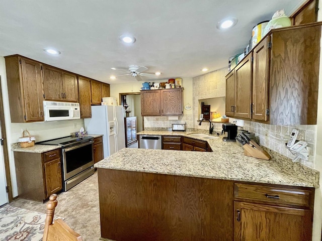 kitchen with a peninsula, recessed lighting, a sink, stainless steel appliances, and tasteful backsplash