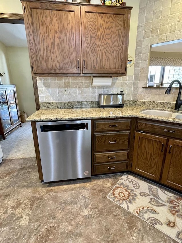 kitchen featuring a sink, decorative backsplash, light stone counters, and dishwasher