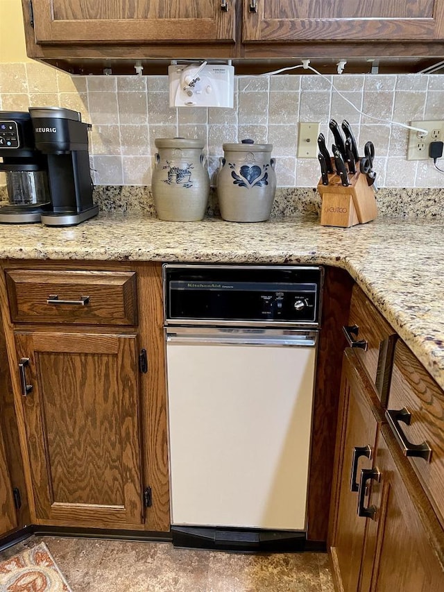 kitchen featuring decorative backsplash, light stone countertops, and brown cabinets