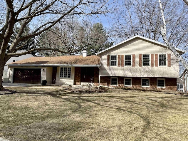 tri-level home featuring an attached garage, a chimney, driveway, and a front yard