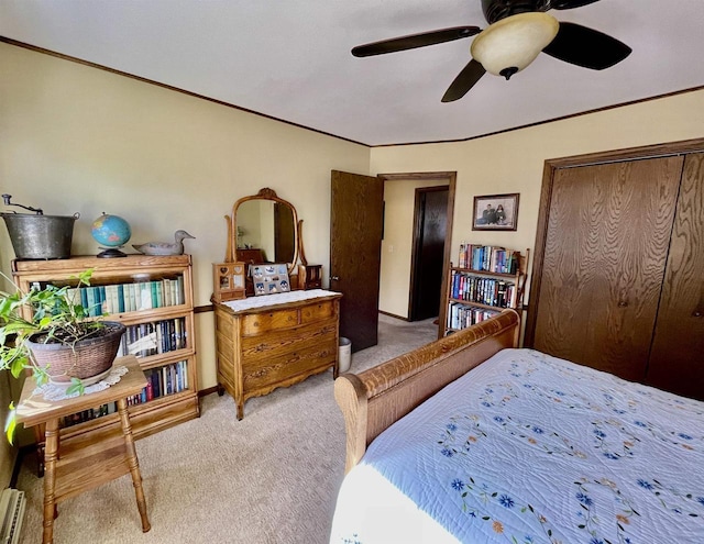 bedroom featuring ceiling fan, a closet, light carpet, and ornamental molding