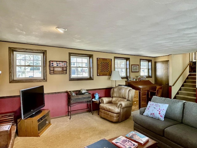 carpeted living room featuring a wealth of natural light, stairway, a textured ceiling, and a wainscoted wall