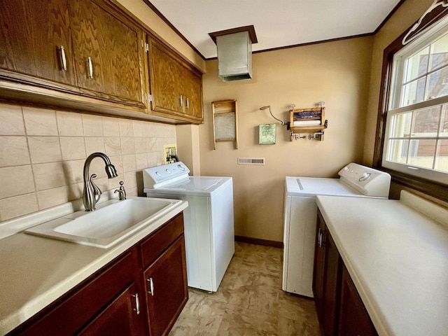 laundry room with cabinet space, ornamental molding, washing machine and dryer, and a sink