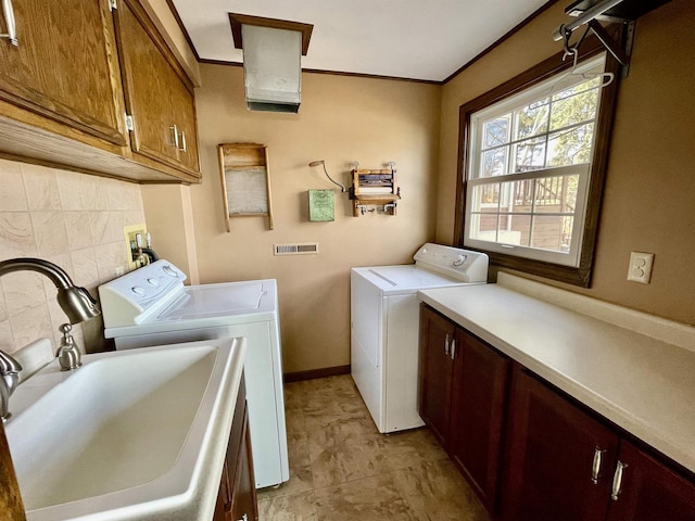 laundry room featuring washer and dryer, cabinet space, crown molding, and a sink