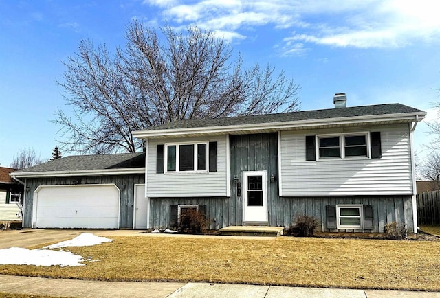 split foyer home featuring a front lawn, an attached garage, and a chimney