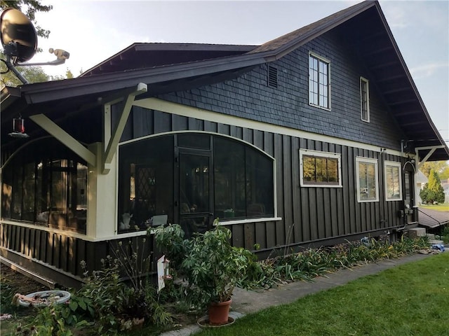 view of property exterior with board and batten siding and a sunroom