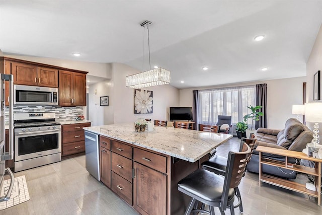 kitchen featuring open floor plan, backsplash, a kitchen breakfast bar, and stainless steel appliances