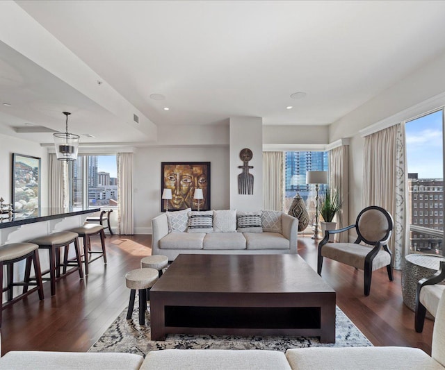 living room featuring a city view, recessed lighting, visible vents, and wood finished floors