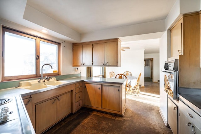 kitchen with oven, light countertops, concrete flooring, a peninsula, and a sink