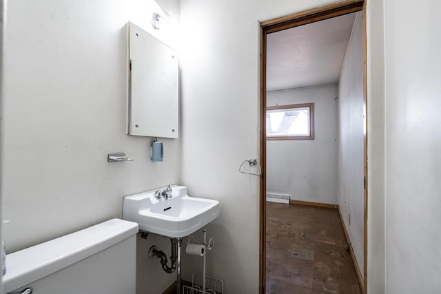 half bath with a sink, a baseboard radiator, and toilet