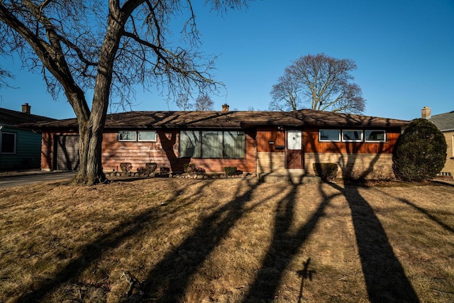 rear view of property featuring a garage, a chimney, and a yard