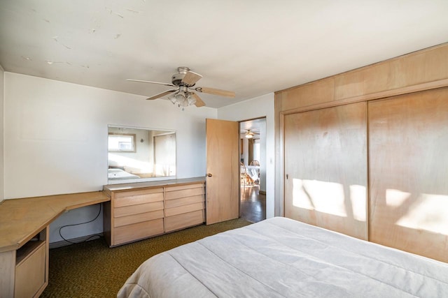 bedroom featuring dark colored carpet, a closet, ceiling fan, and built in desk