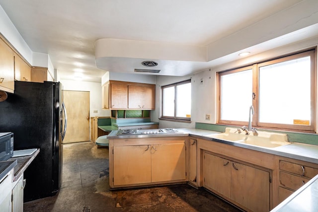 kitchen with black appliances, light countertops, concrete flooring, and a sink