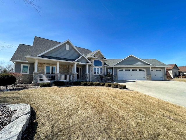 craftsman inspired home featuring stone siding, covered porch, concrete driveway, and an attached garage