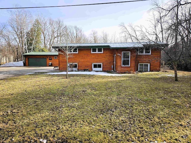 view of front of home with faux log siding, an attached garage, driveway, and a front lawn