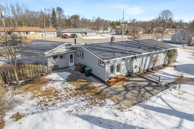 exterior space featuring fence, a residential view, entry steps, french doors, and metal roof