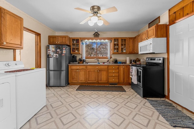 kitchen featuring light floors, washing machine and clothes dryer, stainless steel appliances, glass insert cabinets, and brown cabinets