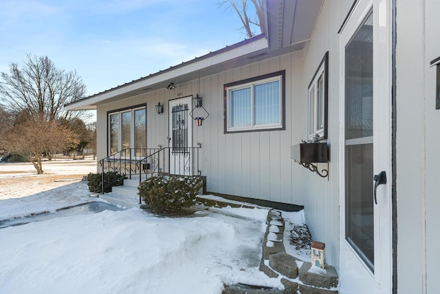 snow covered property entrance with metal roof