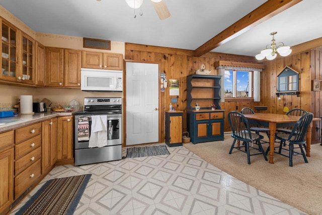 kitchen featuring visible vents, electric stove, light floors, wood walls, and white microwave