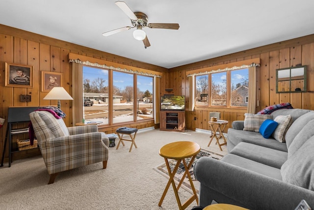 living area featuring light carpet, wooden walls, and ceiling fan