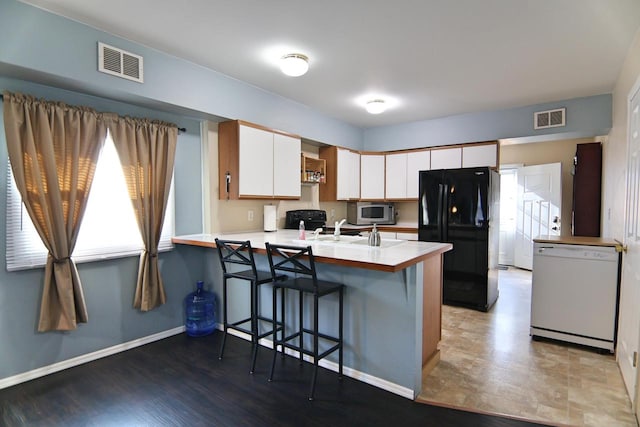 kitchen featuring white cabinetry, black appliances, a peninsula, and visible vents