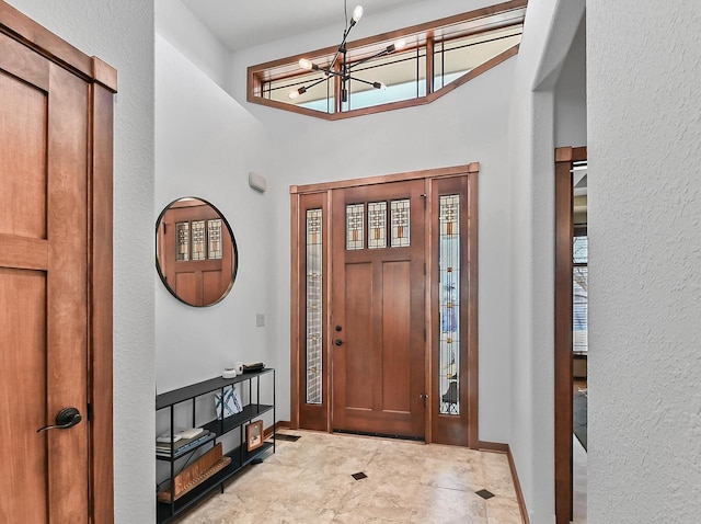 foyer featuring baseboards and a chandelier