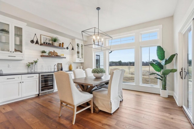 dining area featuring wood finished floors, beverage cooler, and a chandelier