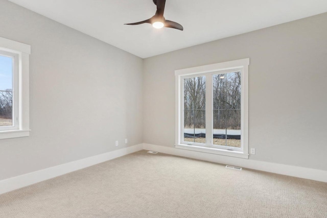 carpeted empty room with visible vents, baseboards, and a ceiling fan