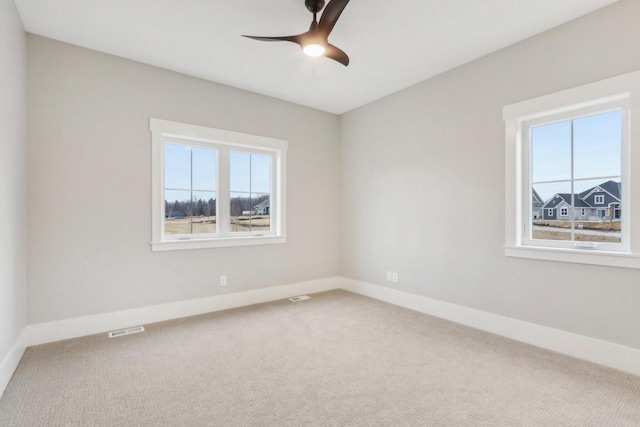 empty room featuring carpet flooring, a healthy amount of sunlight, visible vents, and baseboards