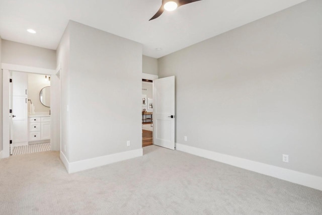 unfurnished bedroom featuring connected bathroom, baseboards, and light carpet