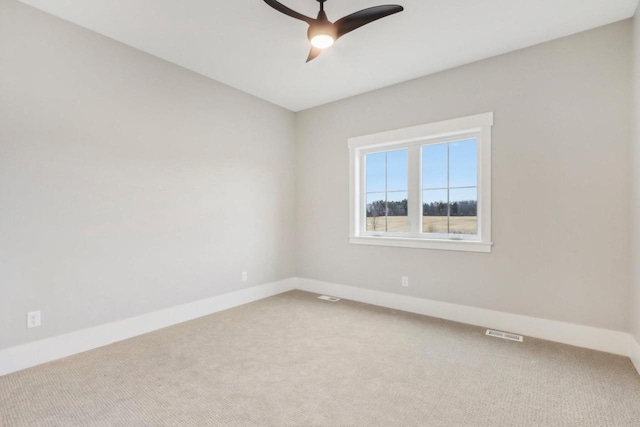 carpeted empty room featuring baseboards, visible vents, and ceiling fan