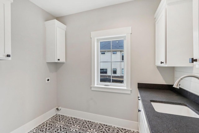 laundry area featuring a sink, baseboards, hookup for an electric dryer, and tile patterned flooring